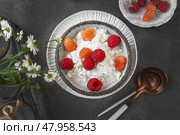 Creamed cottage cheese with raspberries. An easy healthy breakfast. A bowl filled with grainy, creamy cottage cheese is garnished with bright yellow and red raspberries. Top view. Стоковое фото, фотограф Оксана Медведева / Фотобанк Лори