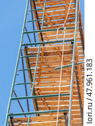 Фасад здания с установленными строительными лесами. Building under construction in scaffolding around the house for cement plastering work on the high outer wall. Стоковое фото, фотограф Татьяна Д / Фотобанк Лори