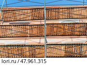 Фасад здания с установленными строительными лесами. Building under construction in scaffolding around the house for cement plastering work on the high outer wall. Стоковое фото, фотограф Татьяна Д / Фотобанк Лори