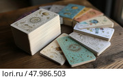 Tarot cards arranged artistically on a wooden table in natural light with mystic symbols and cosmic illustrations. Стоковое AI-изображение, AI-художник Сергей Толмачёв / Фотобанк Лори