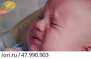 A baby experiences a surprising reaction to solid food for the first time during mealtime at home. The adorable expression shows curiosity mixed with uncertainty. Стоковое видео, видеограф Воловодов Владимир / Фотобанк Лори
