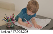 Young child drawing on paper with red marker at home. Стоковое видео, видеограф Константин Шишкин / Фотобанк Лори