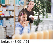 child stands and coughs in the pharmacy, and the mother chooses medications. Стоковое фото, фотограф Яков Филимонов / Фотобанк Лори