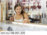 Young woman making choice against the background of stand with knifes. Стоковое фото, фотограф Яков Филимонов / Фотобанк Лори