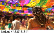 A woman in a vibrant dress enjoys a festive atmosphere filled with colorful decorations and cheerful crowds. Стоковое AI-изображение, AI-художник Данила Большаков / Фотобанк Лори