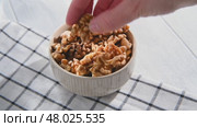 A woman's hand takes a peeled walnut kernel from a bowl filled with walnuts, preparing to enjoy a nutritious and delicious snack rich in protein and healthy fats. Стоковое видео, видеограф Ольга Ильина / Фотобанк Лори