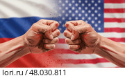 Два сжатых кулака на фоне флагов США и России символизируют конфликт и политическую напряженность между странами, цифровая акварельная иллюстрация. Стоковое AI-изображение, AI-художник Анжелика Самсонова / Фотобанк Лори