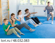 Group of people performing combat strikes sitting during group training. Стоковое фото, фотограф Яков Филимонов / Фотобанк Лори