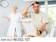 Male patient looks at his reflection in mirror and is upset by ineffective treatment of hair loss. Стоковое фото, фотограф Яков Филимонов / Фотобанк Лори
