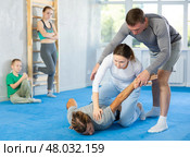 Woman is learning how to grab opponent's hand in prone position during self-defense class, in background girl and boy watch sparring. Стоковое фото, фотограф Яков Филимонов / Фотобанк Лори