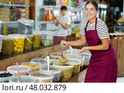 Seller girl in supermarket scooping marinated green olives. Стоковое фото, фотограф Яков Филимонов / Фотобанк Лори