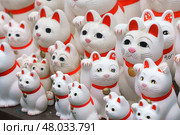 Tokyo, Japan - Sep 30 2024, A close-up view of many multi-sized white beckoning cat figure of Maneki neko with red ears and noses displayed at Gotokuji Temple, without people, at daytime, Tokyo, Japan. Стоковое фото, фотограф Сергей Богомяко / Фотобанк Лори