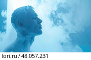 Man with closed eyes standing in a cold steam or cryo environment with blue light. Стоковое AI-изображение, AI-художник Ольга Сухарева / Фотобанк Лори