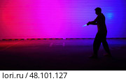 A stunning silhouette with vibrant neon lights and a striking light saber in an artistic setting. Стоковое фото, фотограф David Kashakhi / Фотобанк Лори