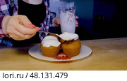 A girl in a plaid shirt is frosting several small cupcakes in the kitchen. Стоковое видео, видеограф Катерина Белякина / Фотобанк Лори