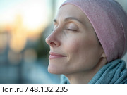 Woman with headscarf closing eyes and breathing fresh air at sunset. Стоковое AI-изображение, AI-художник Юрий Поздников / Фотобанк Лори