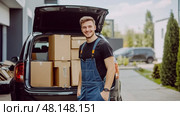 A Cheerful Delivery Worker Handling Boxes and Truck in a Loading Area, Ready to Ensure Efficient Deliveries. Стоковое фото, фотограф Anastasy Yarmolovich / Фотобанк Лори