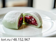 Delicious Japanese moti desserts. Close up. Asian rice daifuku dessert sweet mochi. Cut in half with filling. Traditional dessert mochi ice cream. Colorful rice cake. Fukashi manju. Culinary delights. Стоковое AI-изображение, AI-художник Марина Демидюк / Фотобанк Лори