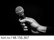 Рука с микрофоном на чёрном фоне. Стоковое AI-изображение, AI-художник Александр Жуков / Фотобанк Лори