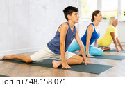 Mother, grandmother and teen son do exercise dove pose, Eka Pada Rajakapotasana. Стоковое фото, фотограф Яков Филимонов / Фотобанк Лори