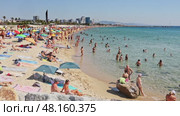 Summer view of lively popular Barceloneta beach with vacationers sunbathing on soft sand and swimming in Mediterranean Sea against backdrop of modern cityscape (2022 год). Редакционное видео, видеограф Яков Филимонов / Фотобанк Лори