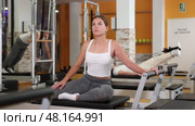 Girl in gym with help of rope reformer performs exercises to strengthen muscles of her arms. Стоковое видео, видеограф Яков Филимонов / Фотобанк Лори