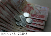 Банкноты номиналом 5000 российских рублей и монеты в 1 российский рубль. Стоковое фото, фотограф Юлия Зырянова / ТАСС / Фотобанк Лори