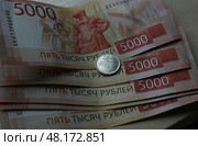 Банкноты номиналом 5000 российских рублей и монета в 1 российский рубль. Стоковое фото, фотограф Юлия Зырянова / ТАСС / Фотобанк Лори