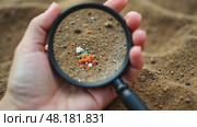 Hand holding a magnifying glass over a patch of dirt. Стоковое AI-видео, аниматор Sergey Grishin / Фотобанк Лори