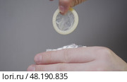 A detailed view of a man's hands, removing a condom from its packaging prior to sexual activity, against a white backdrop. Стоковое видео, видеограф Strunov David / Фотобанк Лори