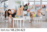 Girl coach shows combination of lap dance movements performed while lying on chair. Стоковое фото, фотограф Яков Филимонов / Фотобанк Лори