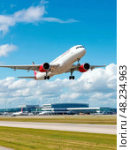 The take-off of a passenger plane, in the distance, the building of a modern airport. Стоковое AI-изображение, AI-художник Сергей Елизарьев / Фотобанк Лори