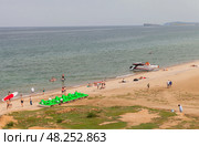 BAIKAL LAKE, OLKHON ISLAND, KHUZHIR VILLAGE, IRKUTSK REGION, RUSSIA - August 03, 2024: People relax on sandy beach of Saraiskiy Bay, ride SUP boards, pleasure boats and water bikes in the summer. Редакционное фото, фотограф Виктория Катьянова / Фотобанк Лори