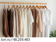 Wooden hangers with clothes on the rail in the store with clothing for sale. Flea market, second hand, discount, exchange, donation. Стоковое AI-изображение, AI-художник Оксана Гильман / Фотобанк Лори