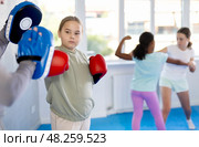 Tween girl in boxing gloves practicing punches on focus mitts with instructor. Стоковое фото, фотограф Яков Филимонов / Фотобанк Лори