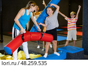 Tween girl fighting by pugil stick with female friend on inflatable beam. Стоковое фото, фотограф Яков Филимонов / Фотобанк Лори