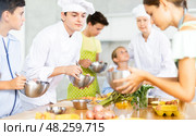 During cooking lesson, male cook tells children about culinary rules, woman assistant helps child. Стоковое фото, фотограф Яков Филимонов / Фотобанк Лори