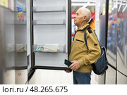 Senor man pensioner buying fridge in showroom of electrical appliance store. Стоковое фото, фотограф Татьяна Яцевич / Фотобанк Лори