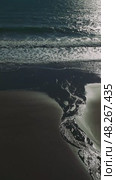 Soft sunset light illuminating dark sandy coastline, golden reflections rippling across wet shore with gentle waves washing over serene oceanfront landscape. Стоковое видео, видеограф ILIA GOROKHOV / Фотобанк Лори