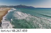 Turquoise waves breaking softly near sandy coast, mount athos rising majestically under summer sky, revealing tranquil mediterranean seascape with stunning natural beauty. Стоковое видео, видеограф ILIA GOROKHOV / Фотобанк Лори