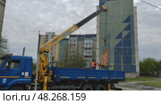 Автокран манипулятором загружает ограждения в кузов, рабочий контролирует груз, Ленинский район, Екатеринбург. Редакционное видео, видеограф Vladislav_v / Фотобанк Лори