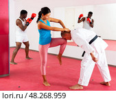 Woman is practicing self-defence fight in pair with trainer in gym. Стоковое фото, фотограф Яков Филимонов / Фотобанк Лори