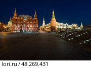 Манежная площадь, Москва, Россия. Вечерний вид на здание Государственного исторического музея и башни Московского Кремля. Исторический центр города. Размытые фигуры людей на длинной выдержке. (2023 год). Редакционное фото, фотограф Андрей Степанов / Фотобанк Лори