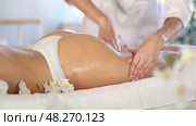 Closeup of hands of professional masseuse performing anti-cellulite massage on buttocks and thighs of young female client at spa center. Стоковое видео, видеограф Яков Филимонов / Фотобанк Лори