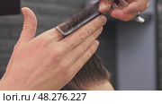 Hairdresser collects hair on the client's head into bun and then uses scissors to cut split ends, as well as to trim overall haircut. Стоковое видео, видеограф Strunov David / Фотобанк Лори