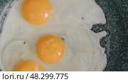 The egg sizzles as it hits the hot pan, the clear liquid slowly turning white and firm around the bright yellow yolk. Стоковое видео, видеограф Алексей Круковский / Фотобанк Лори