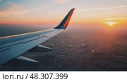 Captivating sunset view from an airplane wing over a sprawling city landscape. Стоковое AI-видео, аниматор Ekaterina Ismagilova / Фотобанк Лори