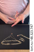 A woman reviewing jewelry, laying out a gold-colored necklace, bracelet, earrings, and ring on a table. Vertical video. Стоковое видео, видеограф Vadzim Yakubovich / Фотобанк Лори