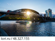 Городской пейзаж Москвы-реки и Лужнецкого моста. По мосту идет поезд, а под мостом проплывает теплоход. Современный транспорт Москвы. Стоковое фото, фотограф Константин Григорьев / Фотобанк Лори