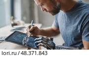 Engineer with bionic arm designing on tablet. Стоковое AI-видео, аниматор Юрий Поздников / Фотобанк Лори
